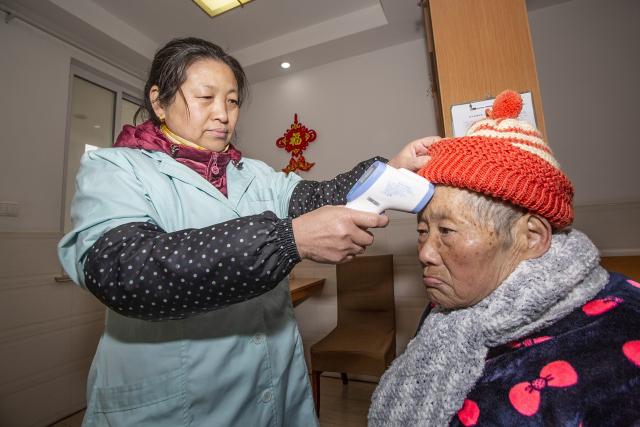 左图为医护人员正在为老人测量体温. 吴贵民 摄
