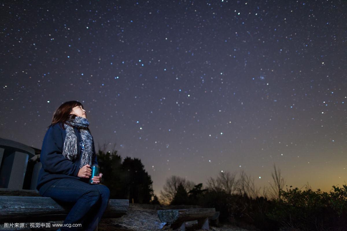 一个女人坐在长凳上仰望星空