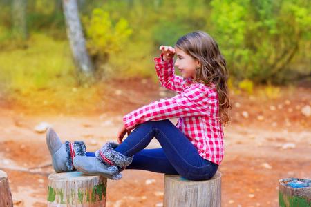 孩子女孩坐在森林树干很远的地方看照片