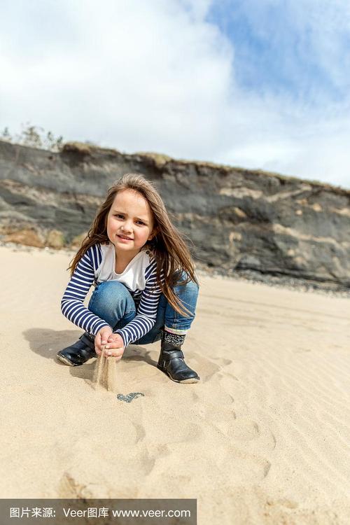 一个六岁小女孩蹲在沙滩上