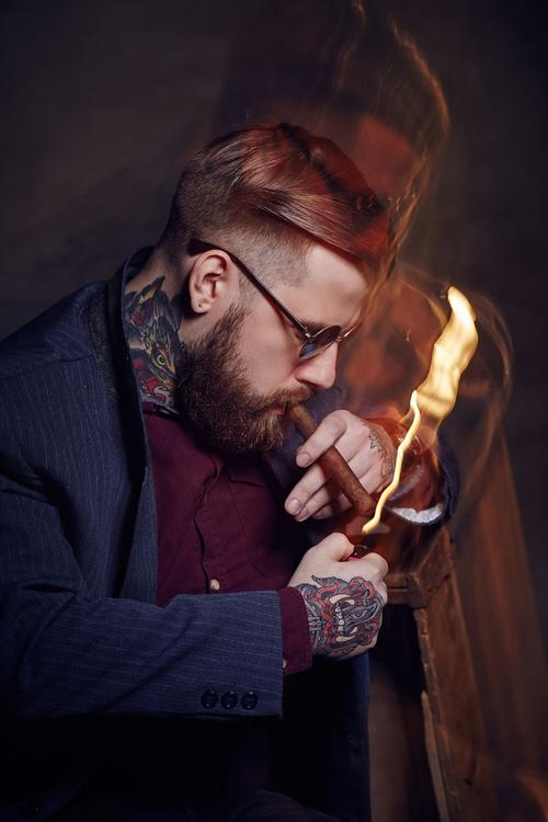 纹身的男性吸烟雪茄