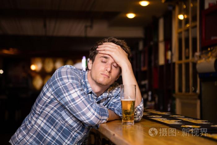 单身男人坐在酒吧喝啤酒